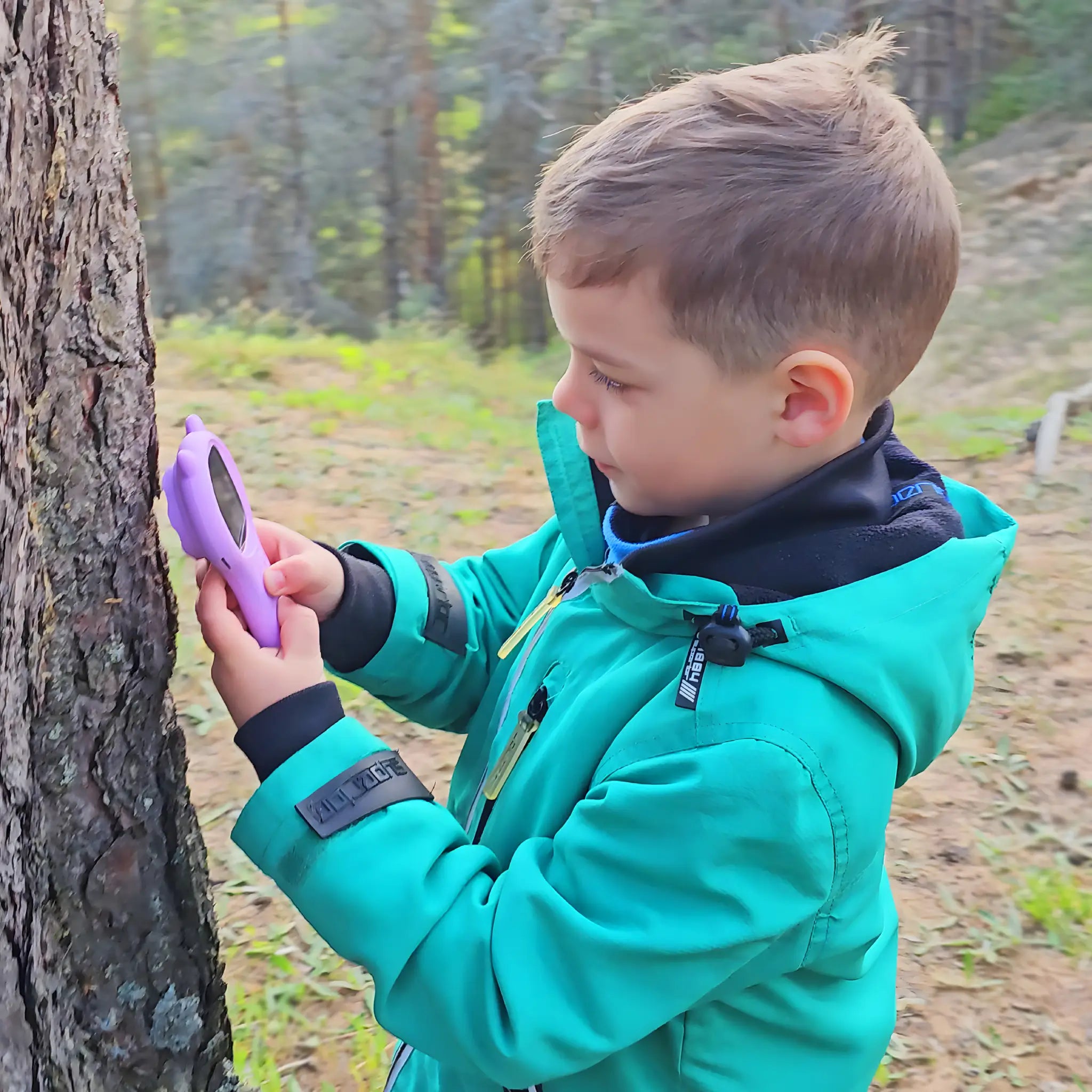 Boy using a handheld kids digital microscope to inspect tree bark in the forest