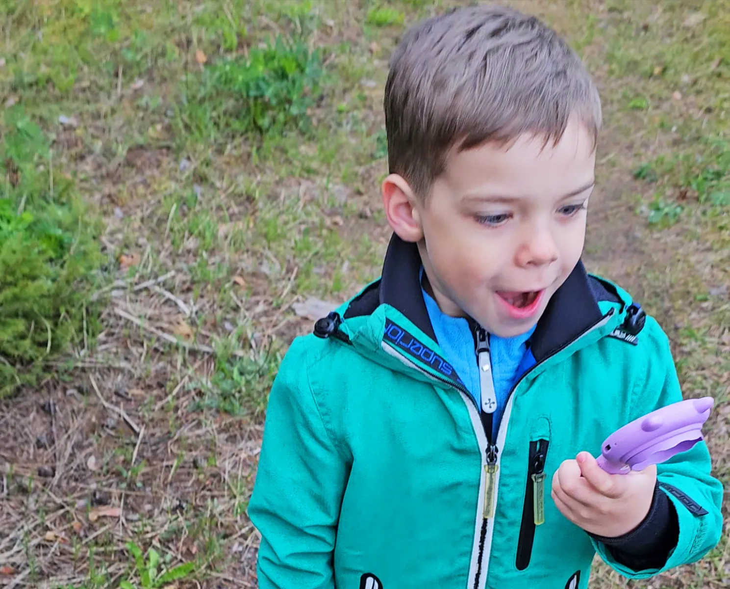 Child outdoors holding a kids digital microscope and reacting with excitement after exploring nature up close